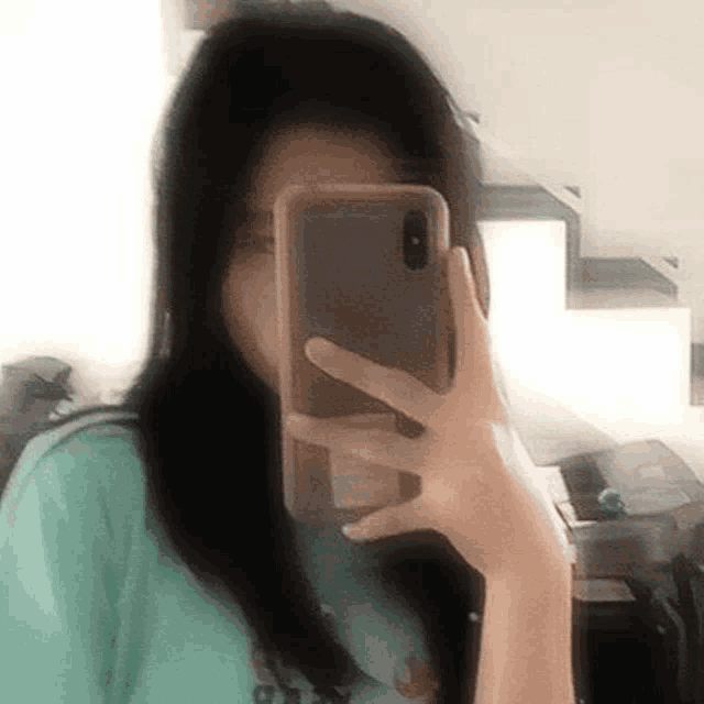 a woman is taking a selfie with her cell phone in front of her face .