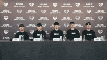 a group of young men are sitting at a table with bottles in front of a wall that says gen.g lol team