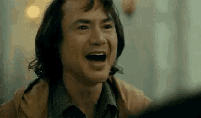 a man is laughing with his mouth open in a close up of his face .