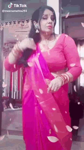 a woman in a pink saree is standing in front of a door .