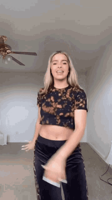 a woman is dancing in a living room with a ceiling fan in the background .