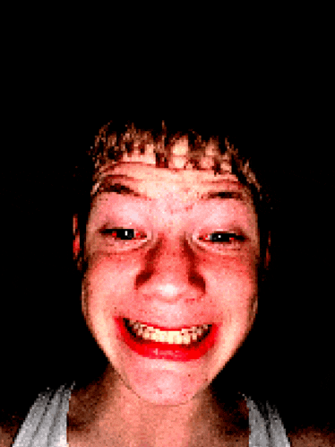 a young man with braces on his teeth is smiling in the dark