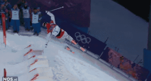 a skier in a red shirt with the number 7 on it is doing a trick in the snow