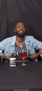 a man is sitting at a table with a glass of wine and a mug .