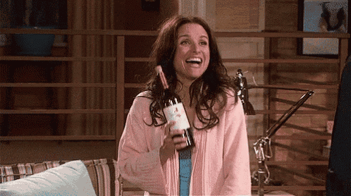a woman in a pink robe holding a bottle of wine