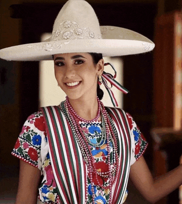 a woman wearing a sombrero and a striped shirt smiles at the camera
