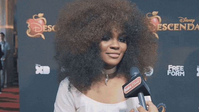 a woman with a microphone and the name china anne mcclain on the bottom