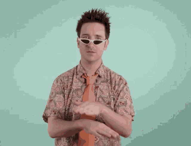 a man wearing sunglasses and a tie is making a gesture with his hands