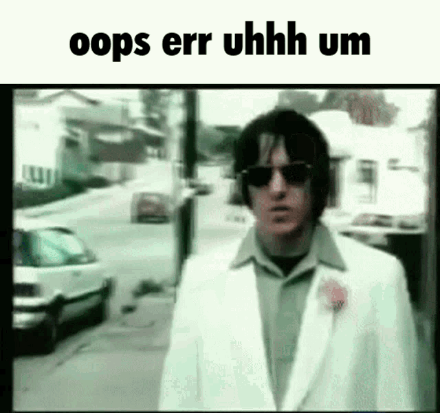 a man in a white suit and sunglasses is walking down a street with the words oops err uhhh um written above him