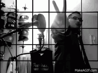 a black and white photo of a man singing into a microphone in front of a wall of hats and shirts