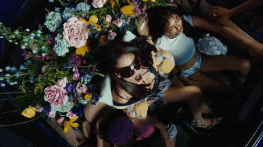 a woman in sunglasses is surrounded by flowers