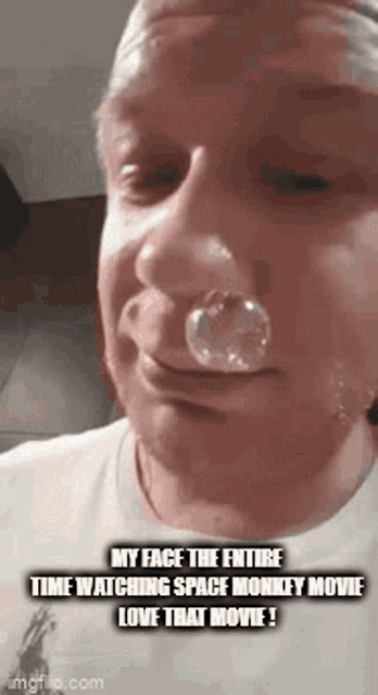 a man with a bubble in his nose is watching space monkey movie .