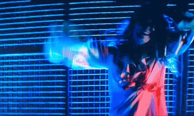 a man is dancing in front of a blue light behind a fence .