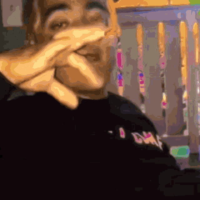 a man is covering his face with his hands while sitting in a chair .