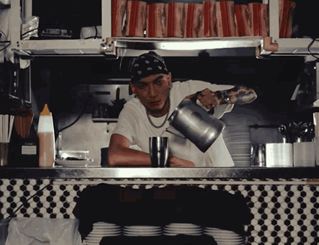 a man wearing a bandana pours liquid into a cup