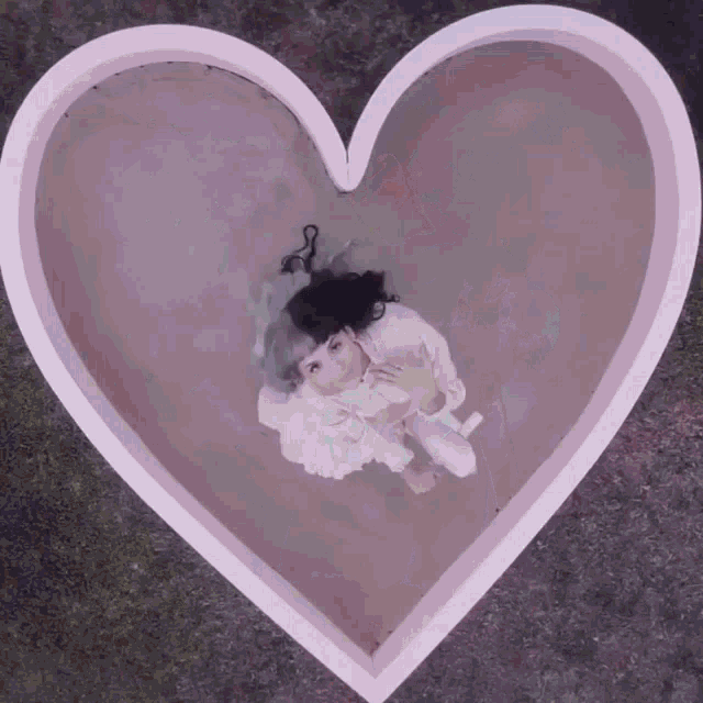 a girl in a white dress is laying in a pink heart