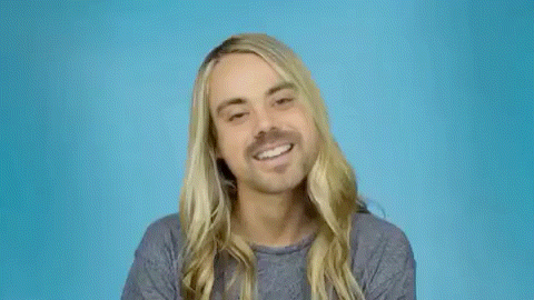 a man with long blonde hair and a beard is smiling and making a funny face .