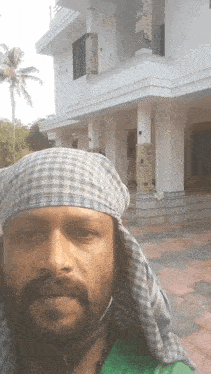 a man wearing a head scarf and a helmet stands in front of a white building