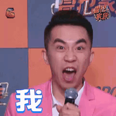 a man in a pink suit is holding a microphone with his tongue out