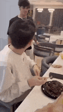 a man is sitting at a table eating a chocolate cake with a spoon .