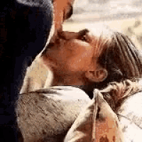 a man is kissing a woman on the neck while laying down .