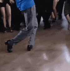 a man in a blue shirt is dancing in front of a crowd of people .