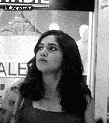 a black and white photo of a woman standing in front of a mannequin in a store .