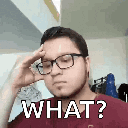 a man wearing glasses and a red shirt is holding his hand to his head and says what ?