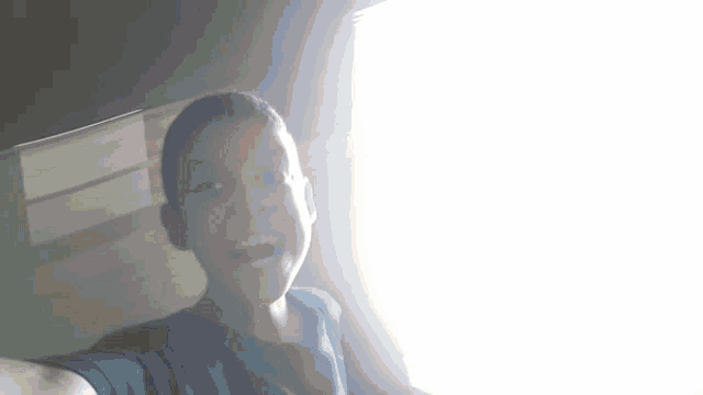 a young boy taking a selfie with a window behind him