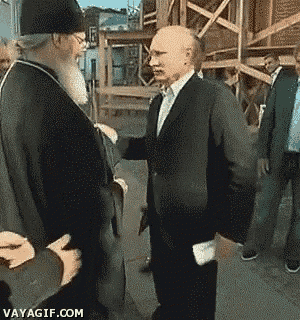 a man in a suit shakes hands with a priest