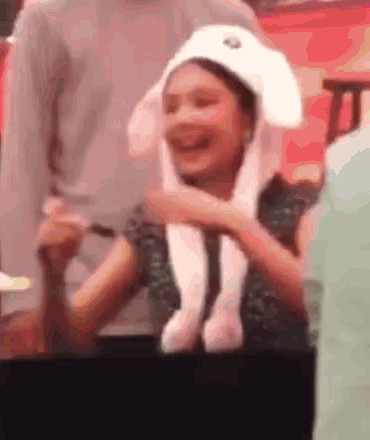 a woman wearing a bunny hat is holding a stuffed animal in her hand .
