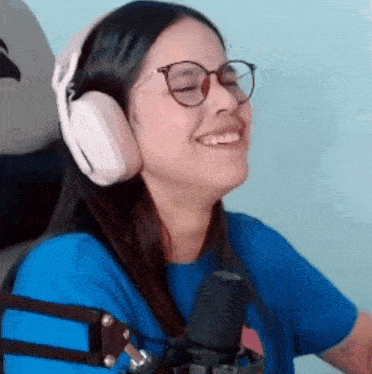 a woman wearing headphones and glasses is sitting in front of a microphone .