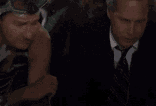 a man in a suit and tie talking to another man