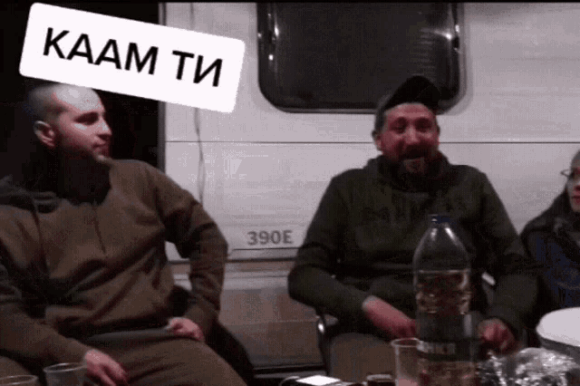 a group of men are sitting in front of a 390e camper