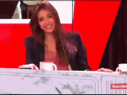 a woman is sitting at a table with two cups of coffee and a sign that says suscribe