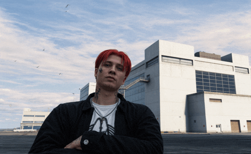 a man with red hair is standing in front of a large white building