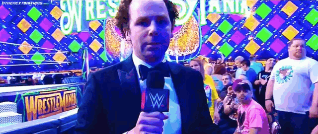 a man in a suit is holding a microphone in front of a crowd of people .