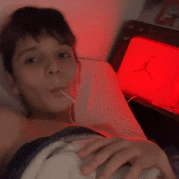 a person laying on a bed with a red air jordan lamp behind them