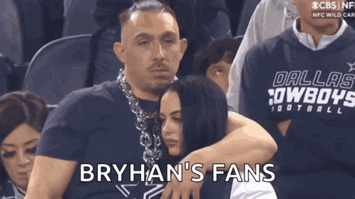 a man in a dallas cowboys sweatshirt is hugging a woman