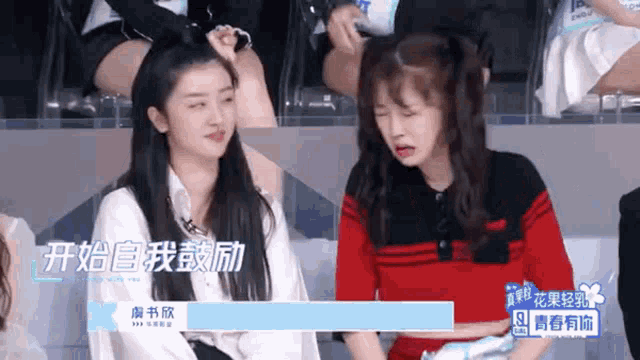 two girls are sitting next to each other and one of them has a sign that says ' i 'm with you ' on it