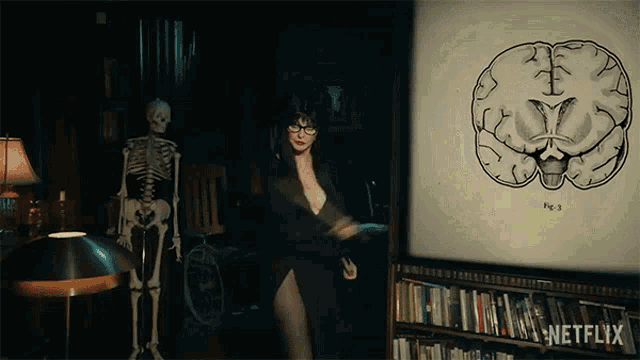 a woman is standing in front of a drawing of a brain and a skeleton in a library .