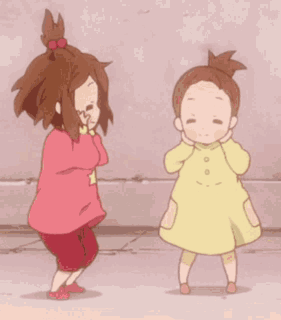 two little girls are standing next to each other and one is covering her face with her hands .