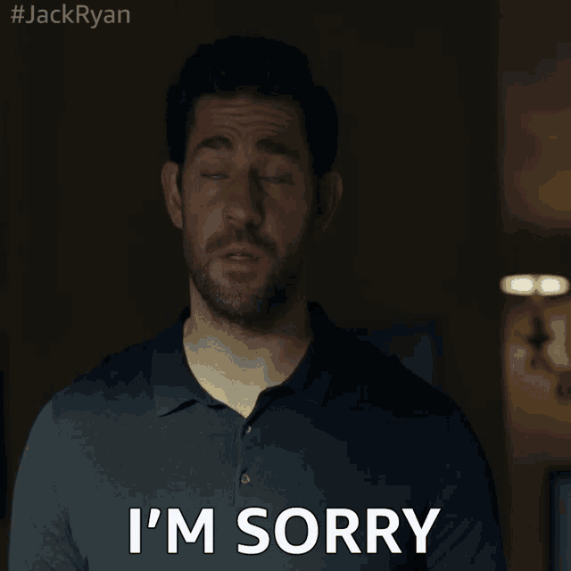 a man with a beard says i 'm sorry in a dark room