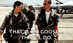 two men in military uniforms are standing next to each other on a runway and talking .
