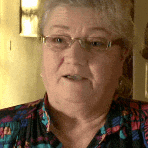 a close up of a woman wearing glasses and a floral shirt