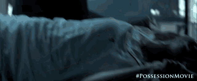 a woman is laying on a bed in a dark room with the words possession movie written on the bottom .