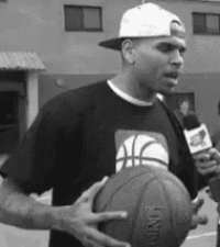 a man wearing a hat is holding a basketball and talking into a microphone