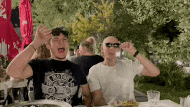 two men are sitting at a table with their mouths open .