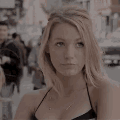 a woman in a black top is standing on a city street .