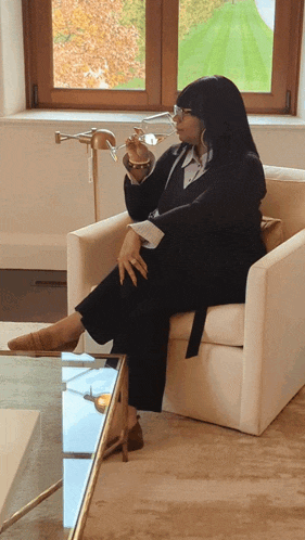 a woman is sitting in a chair holding a glass